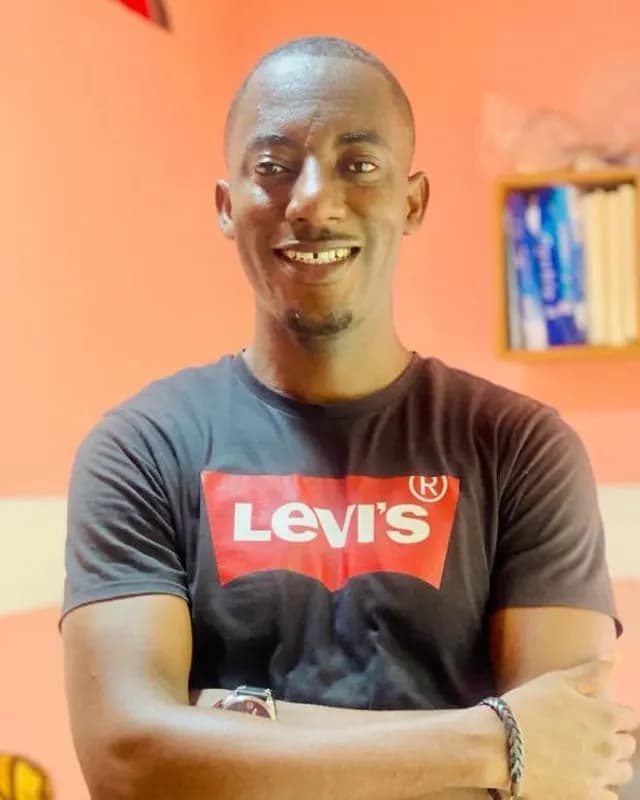Smiling man in a dark T-shirt in front of an orange wall