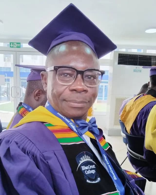 Man in a purple graduation gown and cap with a kente stole