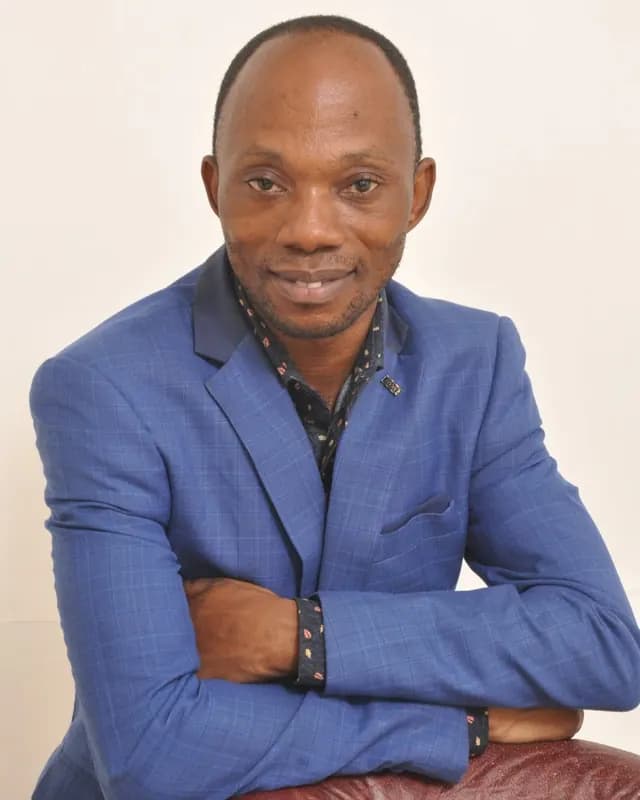 Smiling man in a blue checked blazer with his arms folded