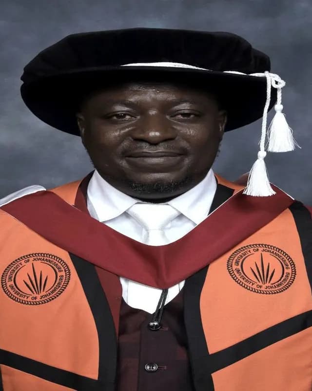 Man in a doctoral cap with white tassels and an orange and maroon gown
